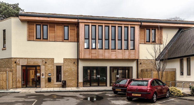 Photo of the completed New Hall, now in use, two cars parked in the car park and the church office lights on